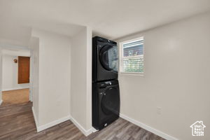 Clothes washing area with stacked washer and dryer and hardwood / wood-style flooring