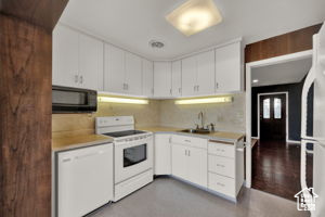 Kitchen with sink, wood-type flooring, white cabinets, and white appliances