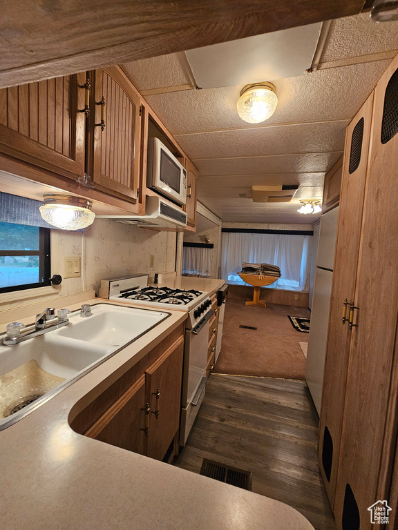 Kitchen featuring sink, dark carpet, and white appliances