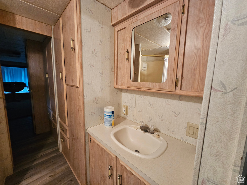 Bathroom with a textured ceiling, vanity, and wood-type flooring