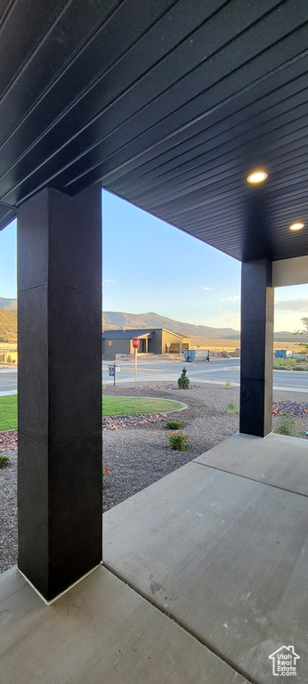 Patio terrace at dusk featuring a water and mountain view