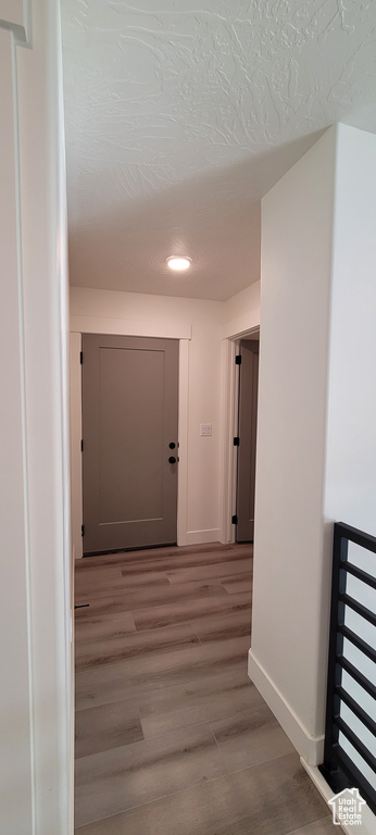 Hallway featuring a textured ceiling and hardwood / wood-style floors