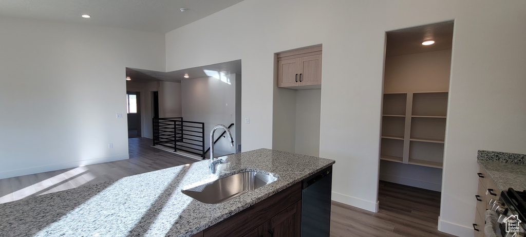 Kitchen featuring light stone counters, sink, wood-type flooring, stainless steel gas range, and dishwasher