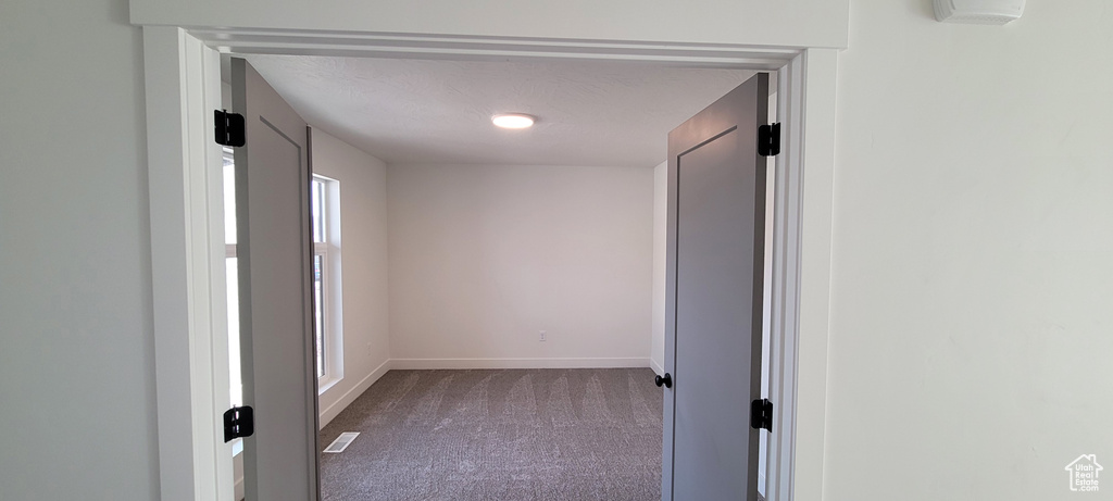 Hallway featuring a textured ceiling and carpet