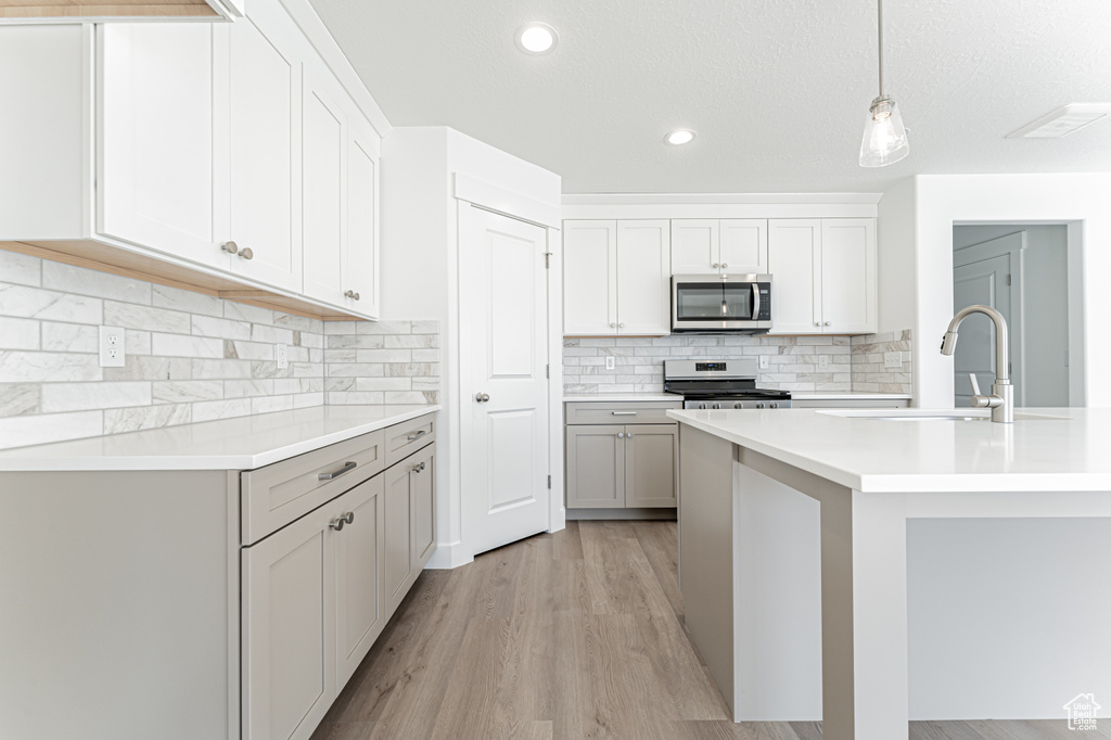 Kitchen featuring appliances with stainless steel finishes, light countertops, a sink, light wood-style floors, and recessed lighting
