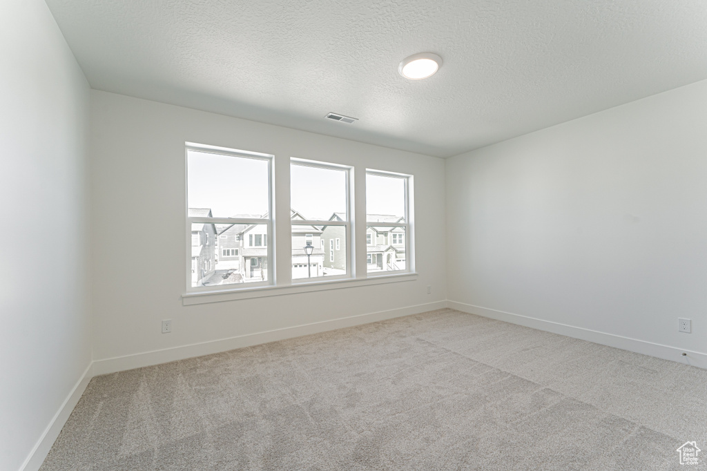 Unfurnished room featuring carpet flooring, a textured ceiling, and baseboards