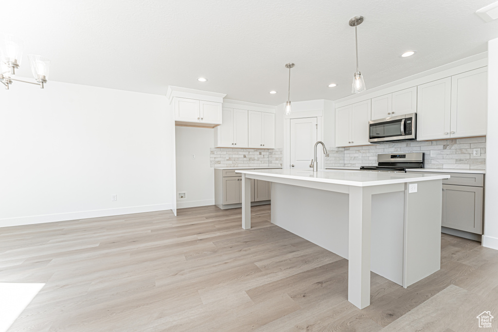 Kitchen with appliances with stainless steel finishes, decorative backsplash, light countertops, light wood-style floors, and recessed lighting