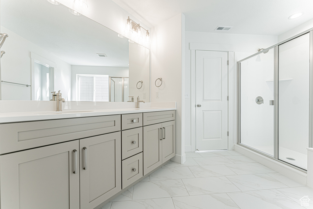 Bathroom featuring double vanity, a stall shower, and marble finish floors
