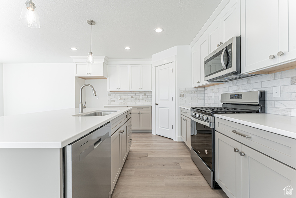 Kitchen with appliances with stainless steel finishes, a sink, recessed lighting, decorative backsplash, and decorative light fixtures