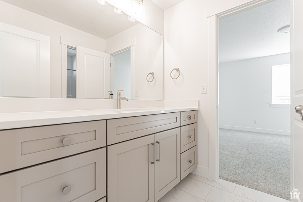 Bathroom featuring vanity, marble look tiles, and baseboards