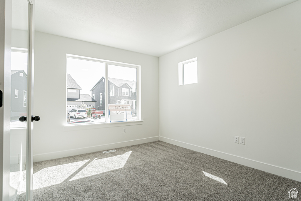 Empty room with baseboards, visible vents, and carpet floors