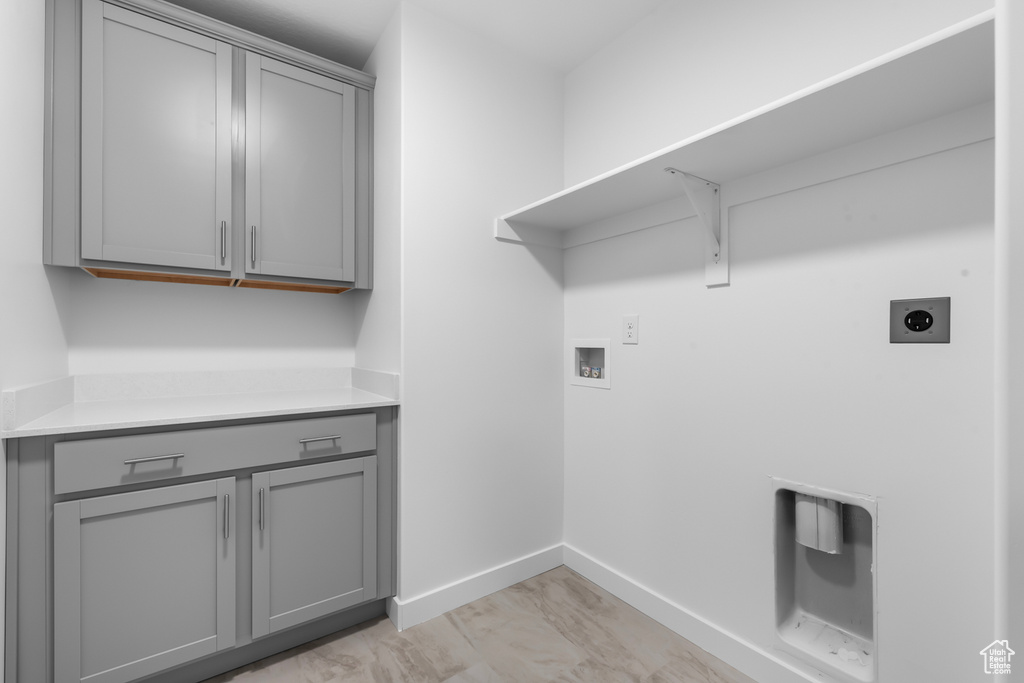 Washroom featuring washer hookup, hookup for an electric dryer, cabinets, and light hardwood / wood-style floors