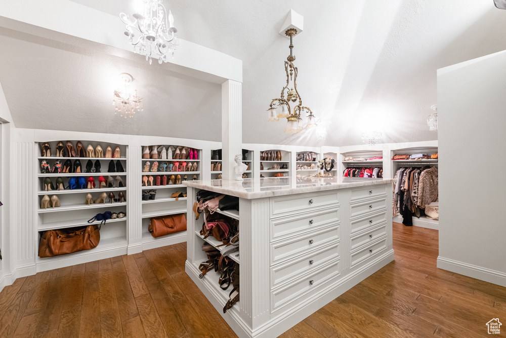 Walk in closet with vaulted ceiling, dark hardwood / wood-style floors, and a notable chandelier