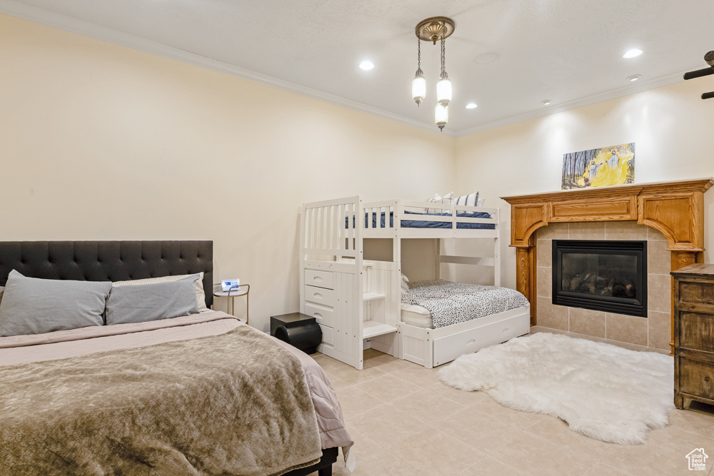 Bedroom featuring a fireplace, crown molding, and light tile patterned floors