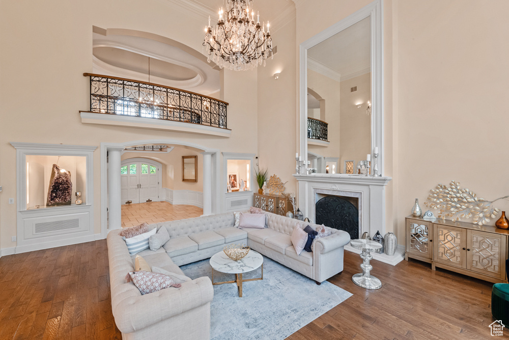 Living room with a chandelier, crown molding, hardwood / wood-style floors, and a towering ceiling