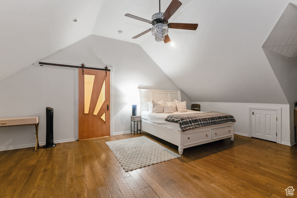 Bedroom with lofted ceiling, ceiling fan, wood-type flooring, and a barn door