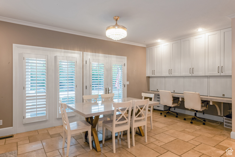 Tiled dining room with an inviting chandelier, a wealth of natural light, and crown molding