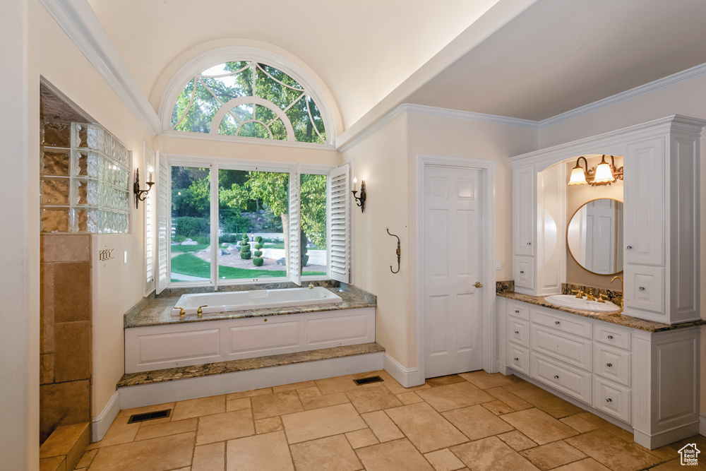 Bathroom with ornamental molding, vanity, a tub to relax in, and tile patterned flooring