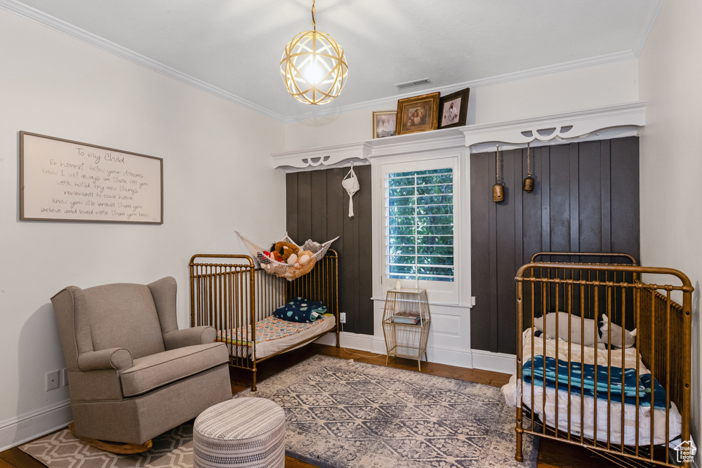 Bedroom featuring a nursery area, crown molding, and hardwood / wood-style flooring