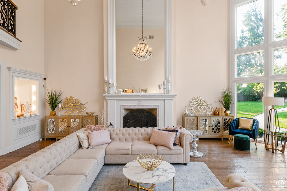 Living room featuring a chandelier, a healthy amount of sunlight, hardwood / wood-style floors, and a towering ceiling