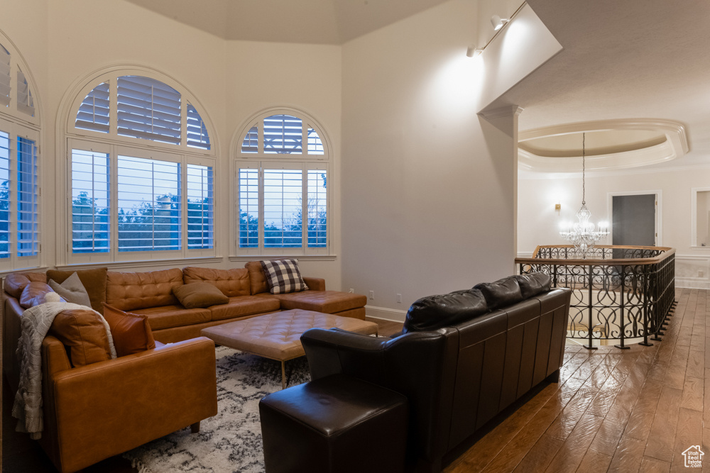 Living room featuring a notable chandelier, hardwood / wood-style floors, and a tray ceiling