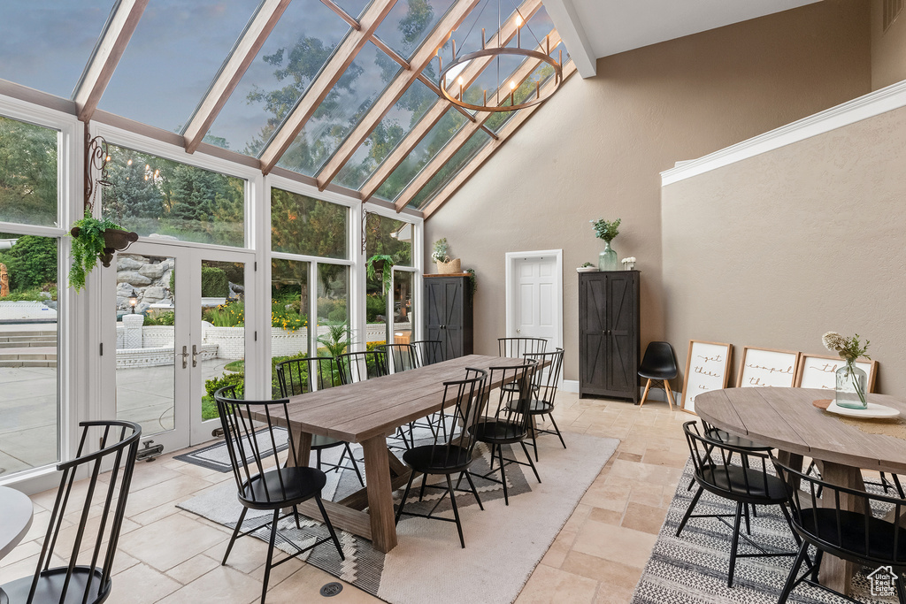 Sunroom featuring lofted ceiling with beams, a wealth of natural light, and french doors