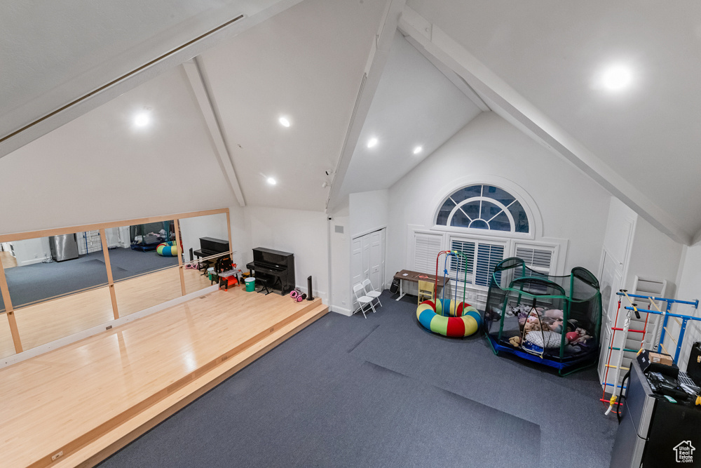 Rec room featuring high vaulted ceiling, beamed ceiling, and carpet