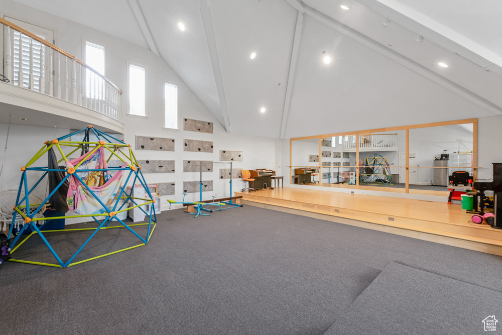 Recreation room with high vaulted ceiling and carpet