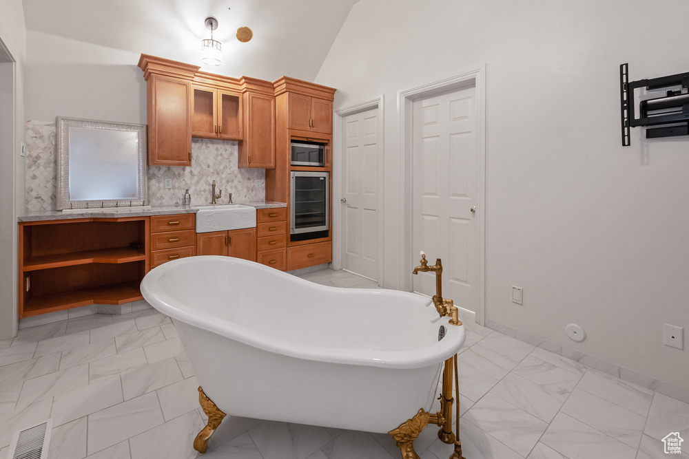 Bathroom with tile patterned flooring, lofted ceiling, decorative backsplash, and vanity