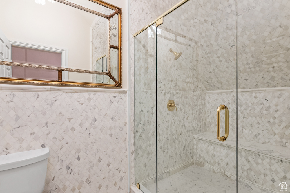 Bathroom featuring toilet, an enclosed shower, and tile walls