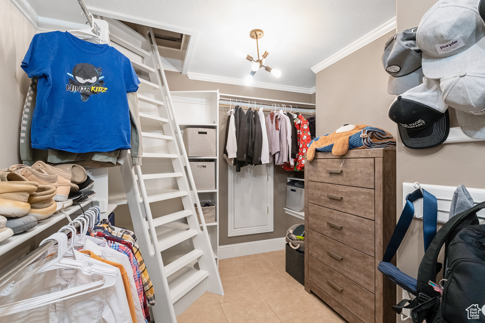 Spacious closet with light tile patterned flooring and a notable chandelier