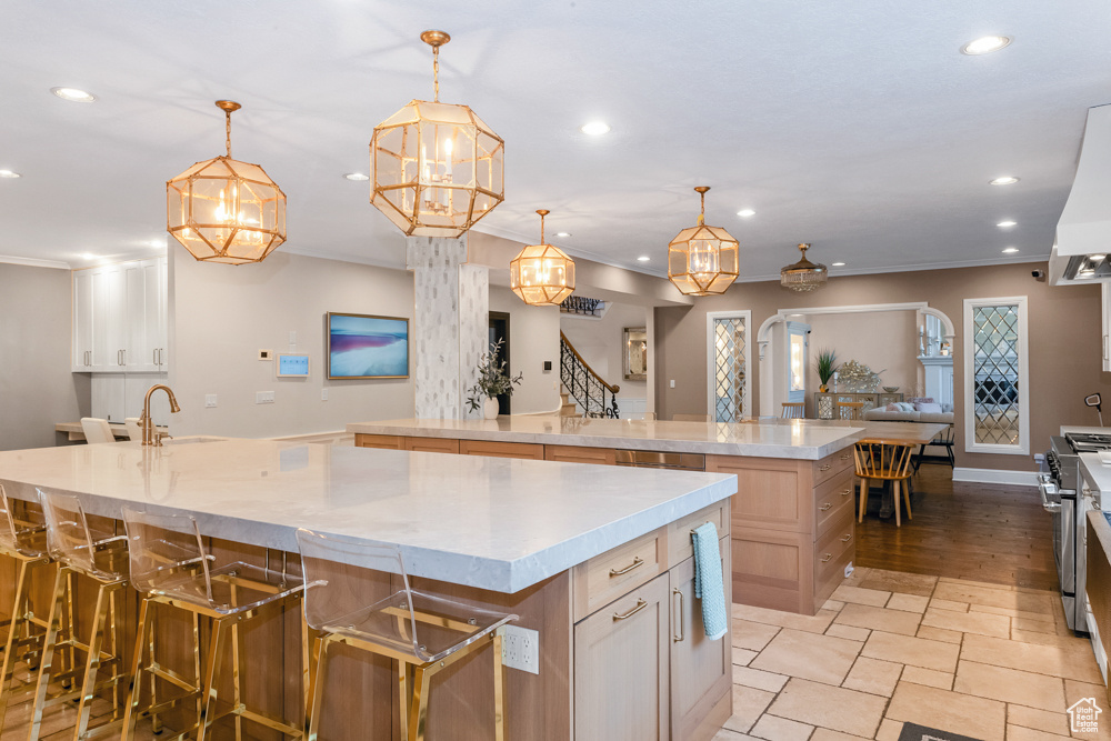 Kitchen featuring a kitchen bar, light hardwood / wood-style flooring, decorative light fixtures, stainless steel gas range oven, and a spacious island