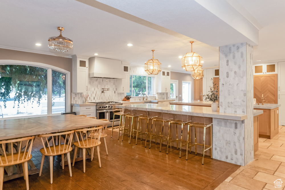 Kitchen featuring white cabinetry, premium range hood, double oven range, and light wood-type flooring