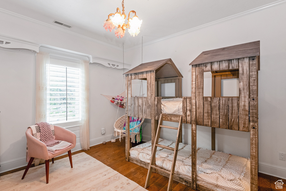 Bedroom featuring hardwood / wood-style floors, a chandelier, and ornamental molding