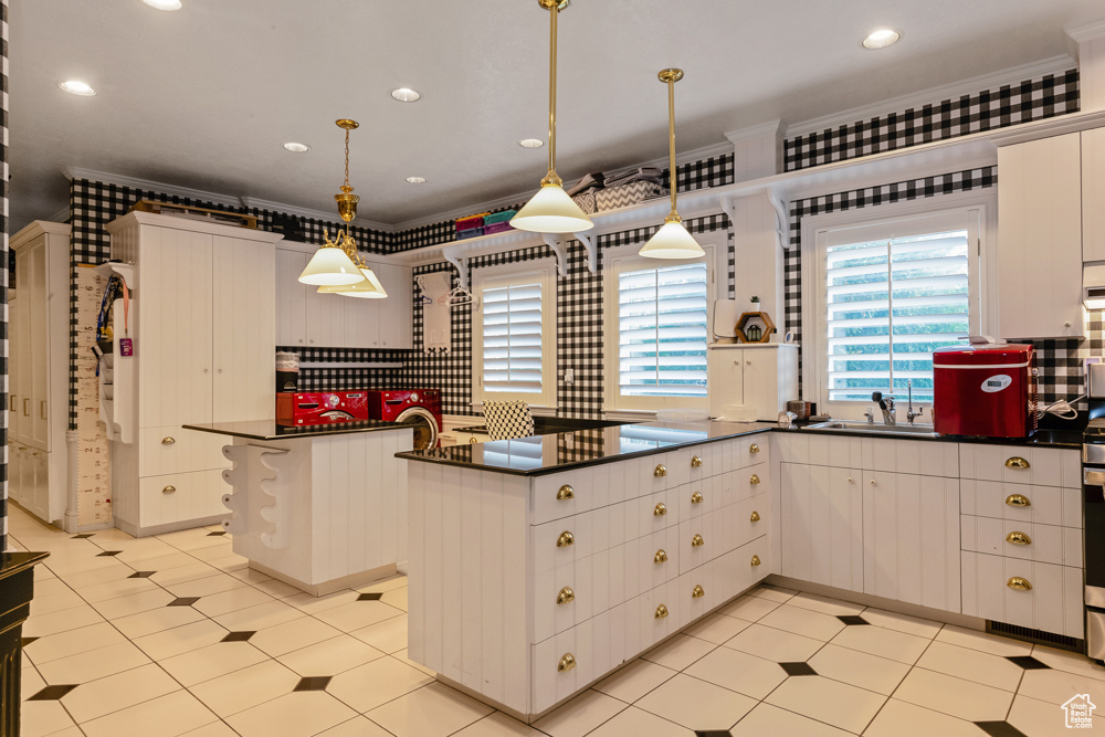 Kitchen featuring sink, light tile patterned floors, ornamental molding, and decorative light fixtures