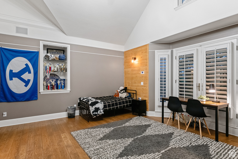 Bedroom with hardwood / wood-style flooring and high vaulted ceiling