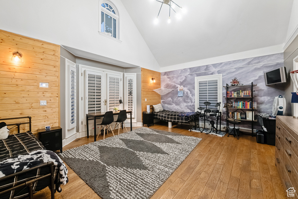 Living room featuring wooden walls, high vaulted ceiling, and light wood-type flooring