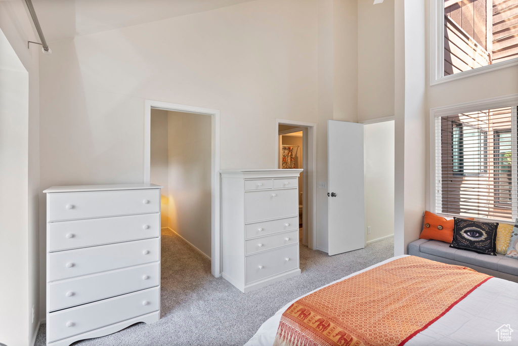 Bedroom featuring a towering ceiling and light colored carpet