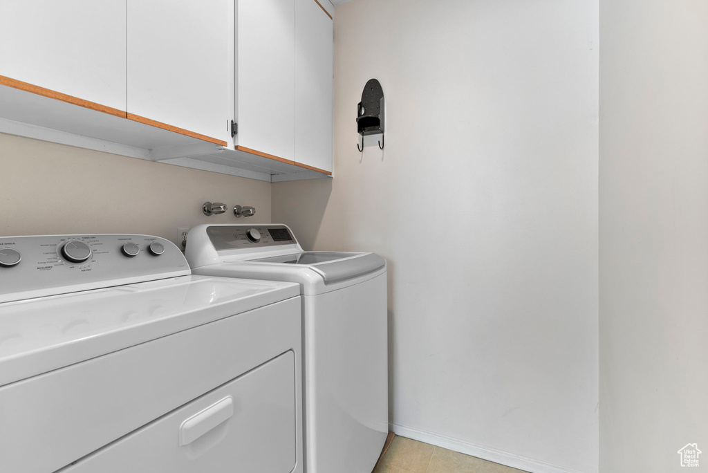 Laundry room featuring light tile patterned flooring, independent washer and dryer, and cabinets