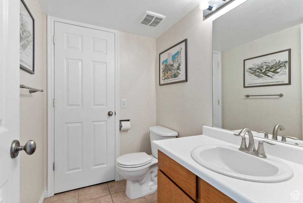 Bathroom featuring vanity, tile patterned flooring, and toilet