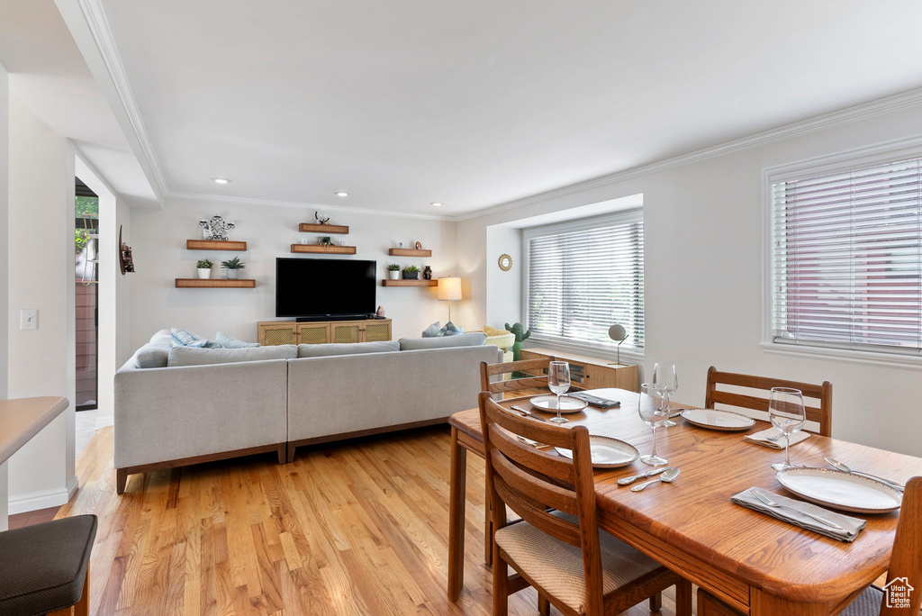 Dining room with ornamental molding and light hardwood / wood-style floors