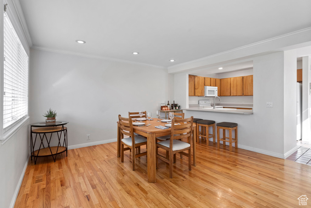 Dining room with light wood-type flooring and ornamental molding