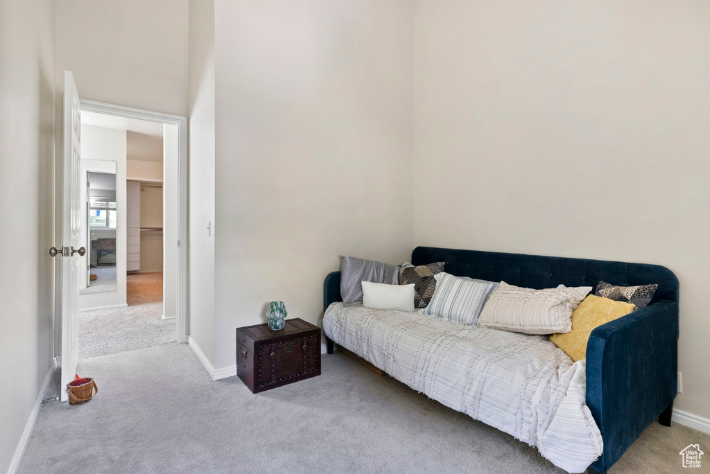 Carpeted bedroom featuring a high ceiling and a walk in closet