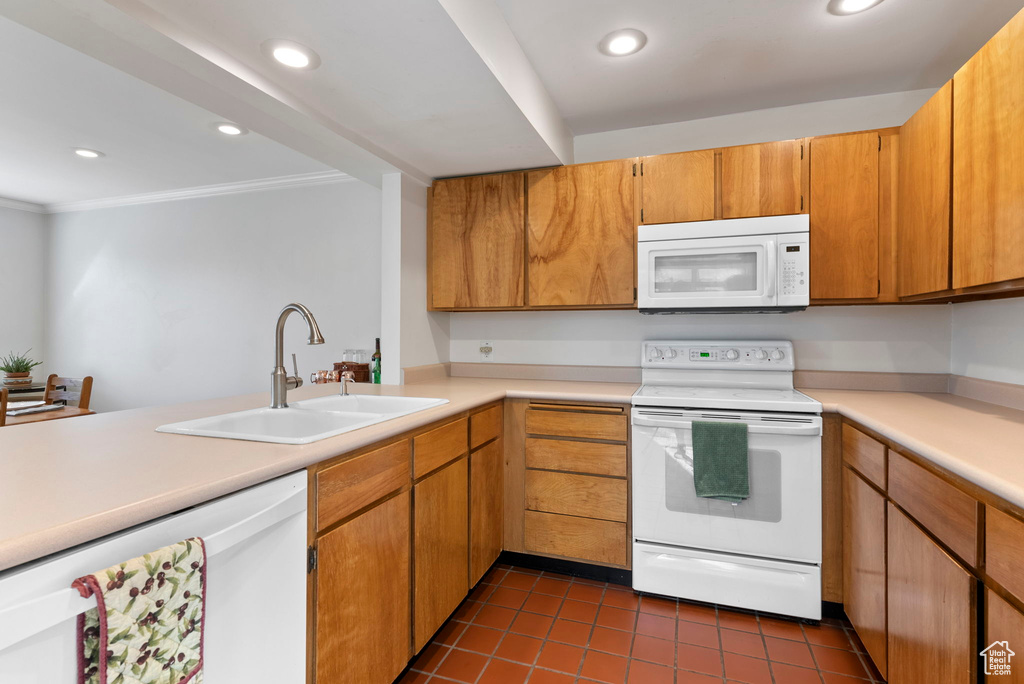 Kitchen featuring white appliances, kitchen peninsula, tile patterned floors, sink, and ornamental molding