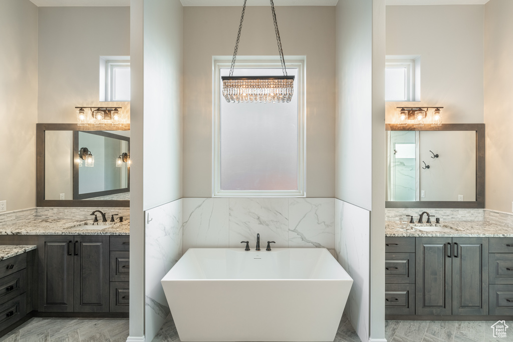 Bathroom with a chandelier, a tub to relax in, and double sink vanity