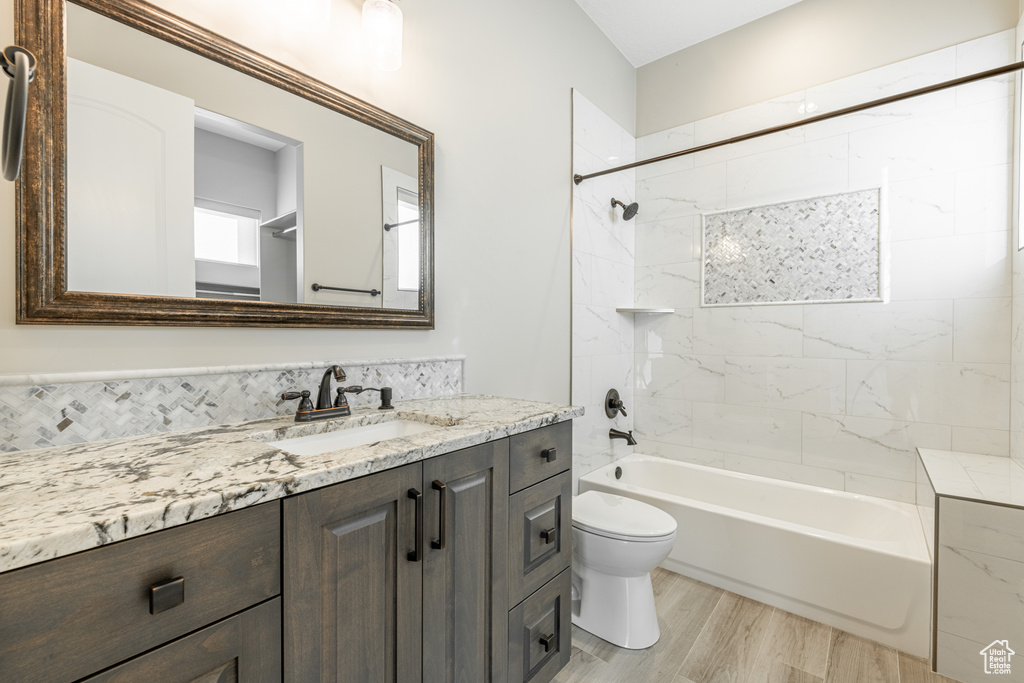 Full bathroom featuring vanity, tiled shower / bath, wood-type flooring, and toilet