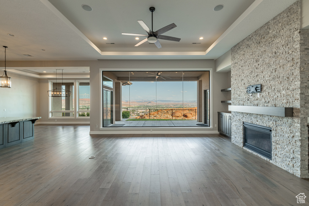 Unfurnished living room with a fireplace, a tray ceiling, hardwood / wood-style flooring, and a wealth of natural light