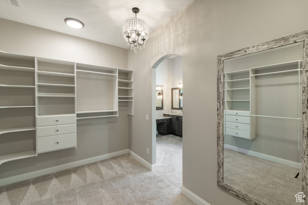 Walk in closet with light carpet and a chandelier