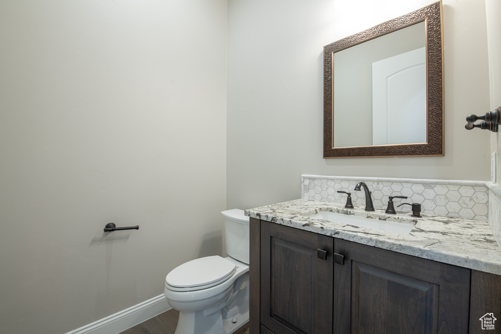 Bathroom featuring vanity, decorative backsplash, and toilet