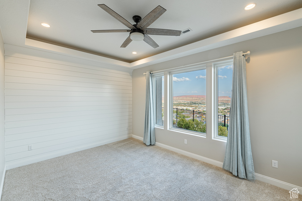 Carpeted spare room with a raised ceiling and ceiling fan